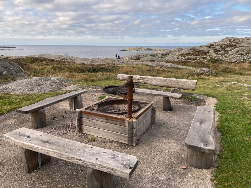 Foto på eldstad med bänkar runtom och havsutsikt.
