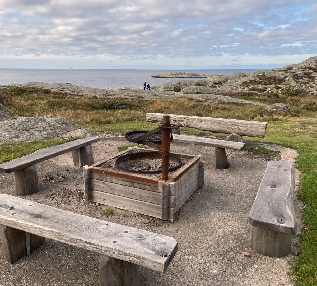 Foto på eldstad med bänkar runtom och havsutsikt.